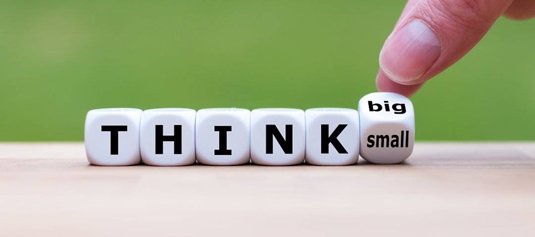 Eine Hand dreht einen Würfel und ändert den Ausdruck "klein denken" in "groß denken". © stock.adobe.com_Fokussiert