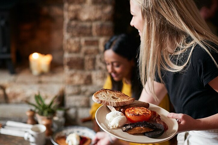 Kellnerin arbeitet in traditionellen englischen Pub serviert Frühstück.