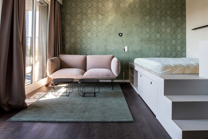 Das Projekt Bohemie von Interboden, realisiert mit Belform, umfasst u.a. ein 38 Quadratmeter großes 1-Zimmer-Apartment mit Podestbett, Sofa, Pantryküche und Balkon/Loggia. © Belform