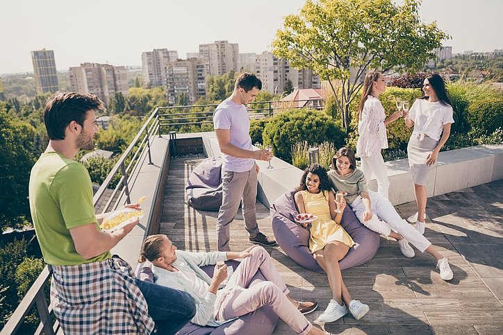 Eine Gruppe junger Leute entspannt auf einer Dachterrasse.
