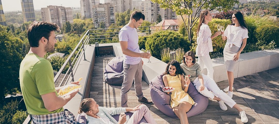 Eine Gruppe junger Leute entspannt auf einer Dachterrasse.