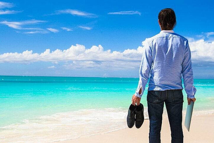 Ein Mann im Hemd steht am Strand.