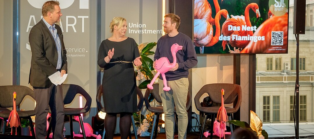 Anett Gregorius und Kai Böcking gratulieren Rafael Weißmüller (r.), Co-Founder von Happyhotel, zum Gewinn des Jury-Preises das "Nest des Flamingos"