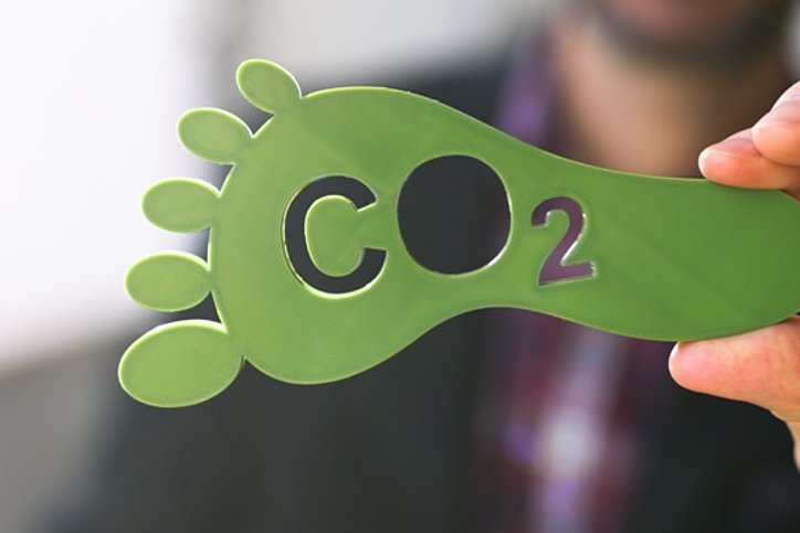 Ein grüner CO2 Fußabdruck wird ins Foto gehalten. Ohne CO2-Fussabdruck und Kompensationen geht im Geschäftsreisesegment bereits nichts mehr. © stock.adobe.com_Andrey Popow