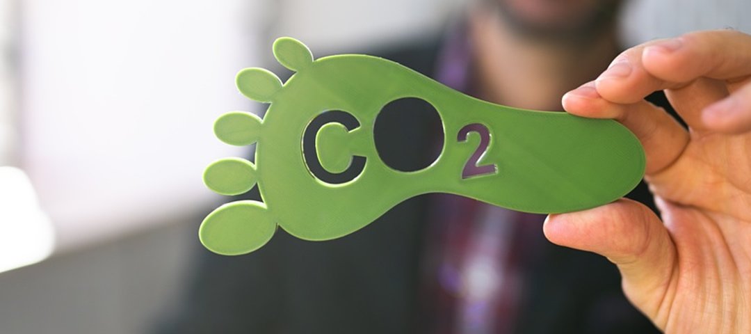 Ein grüner CO2 Fußabdruck wird ins Foto gehalten. Ohne CO2-Fussabdruck und Kompensationen geht im Geschäftsreisesegment bereits nichts mehr. © stock.adobe.com_Andrey Popow