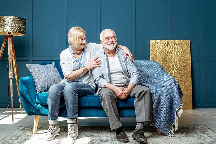 Schönes älteres Paar sitzt zusammen auf der Wohnzimmercouch zu Hause. © stock.adobe.com_ rh2010