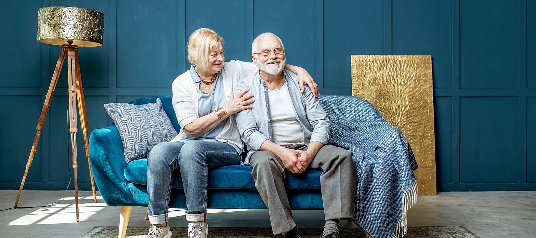 Schönes älteres Paar sitzt zusammen auf der Wohnzimmercouch zu Hause. © stock.adobe.com_ rh2010