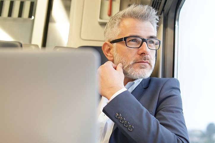 Geschäftsmann sitzt im Zug und schaut aus dem Fenster © stock.adobe.com_goodluz