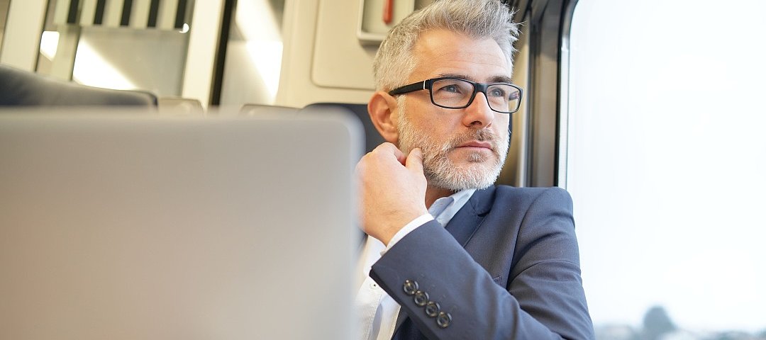 Geschäftsmann sitzt im Zug und schaut aus dem Fenster © stock.adobe.com_goodluz